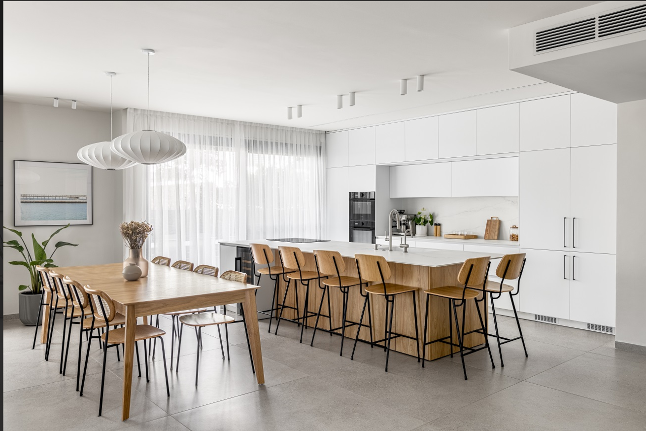 Bright white kitchen with an oak island and long dining table