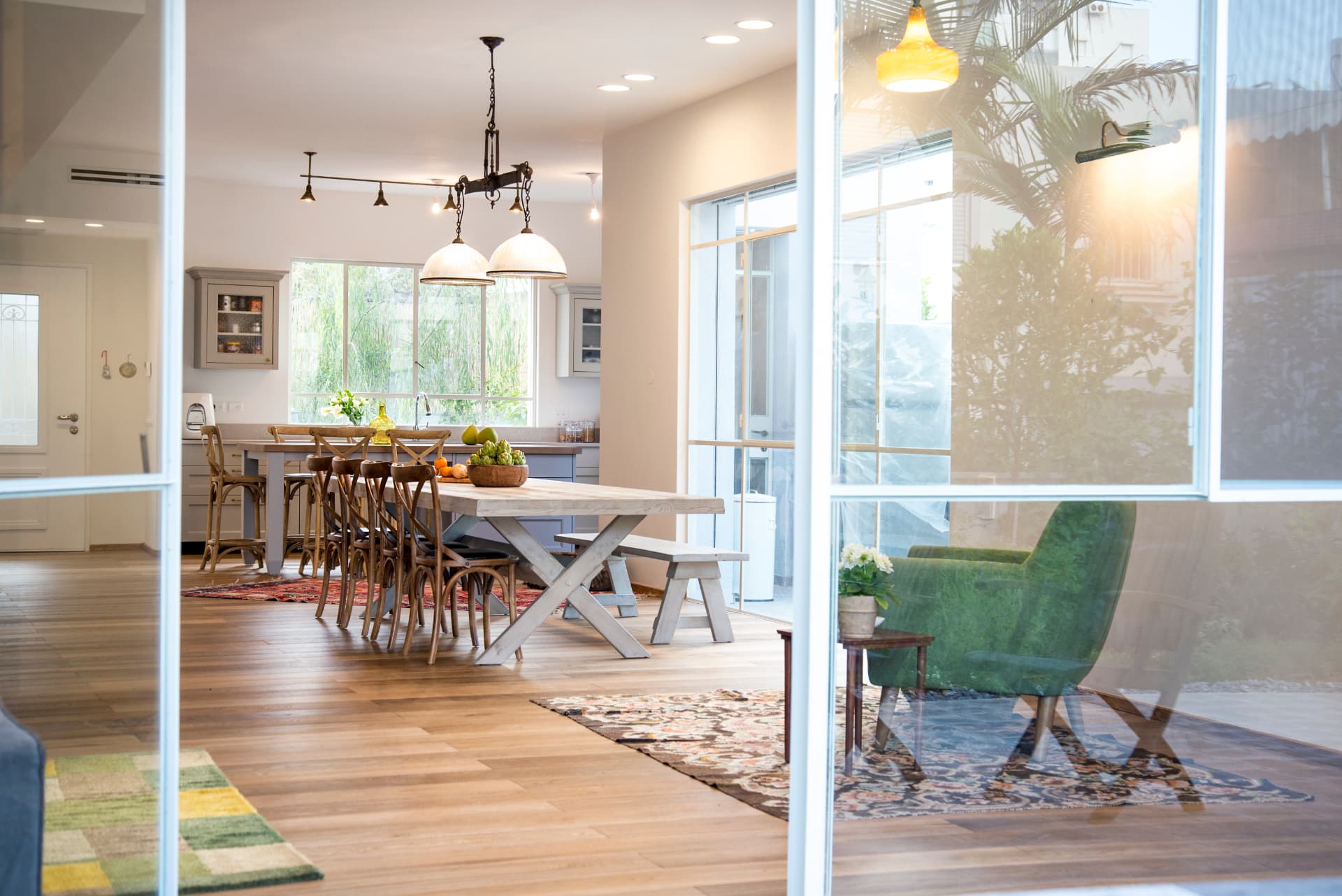 View through a glass door into a dining area and kitchen with light cabinetry