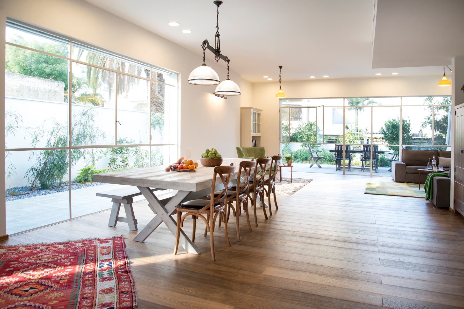 Open plan dining and living space with a wooden dining table, pendant lighting and wood floors
